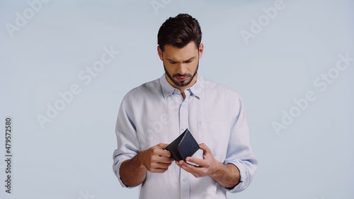 sad man looking at empty wallet isolated on blue photo