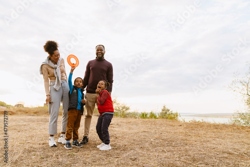 Black family laughing and playing with frisbee during walking