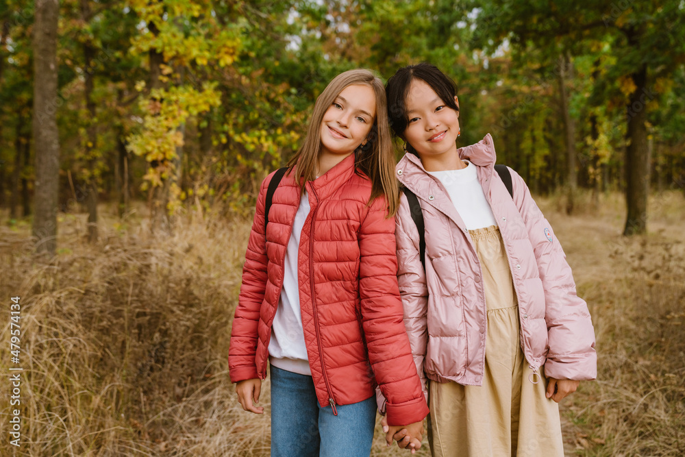 Fototapeta premium Multiracial teenagers holding hands during hiking in autumn forest