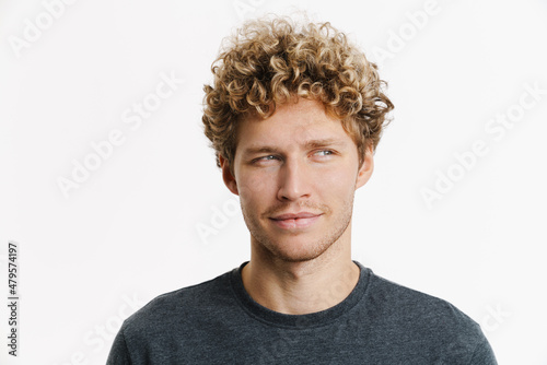 Young blonde man with curly hair smiling and looking aside