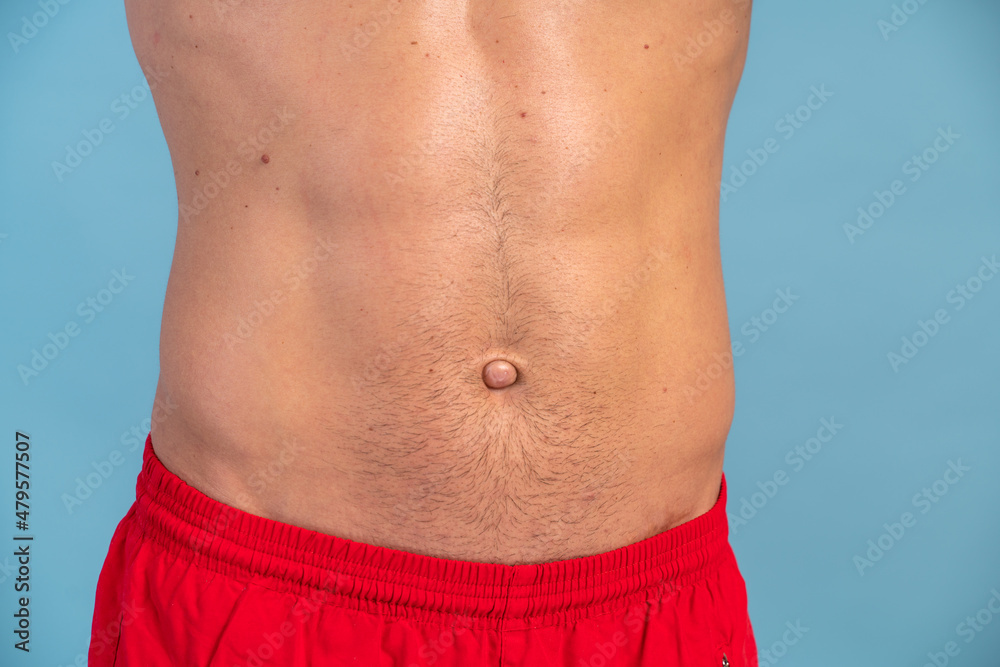Close up view of the stomach of caucasian man with sunburned skin on blue background. Treatment concept. Stock photo