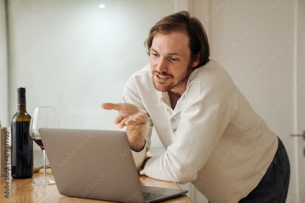 Ginger bristle man using laptop while drinking wine in kitchen Ginger bristle man using laptop while drinking wine in kitchen