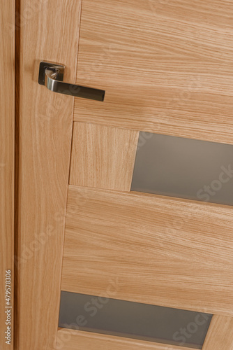Metal door handle on closed natural wooden door