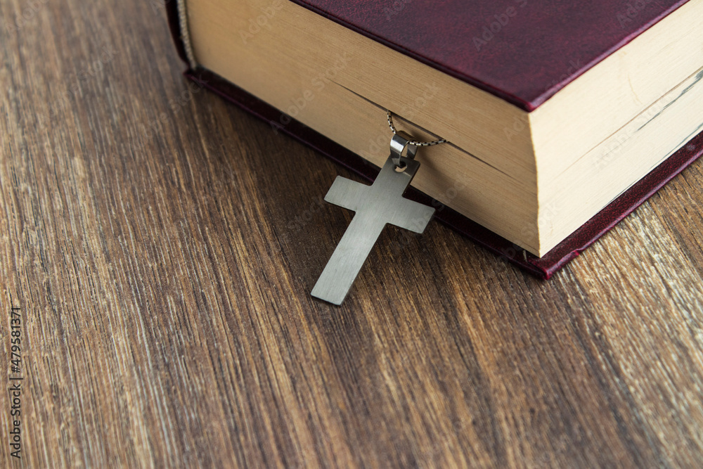 metal cross hang on old bible on wooden background