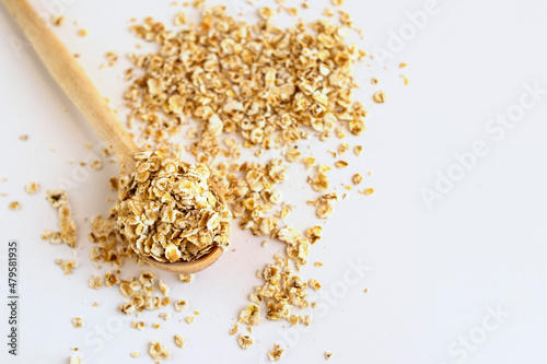 Oatmeal breakfast cereal with wooden spoon on white background macro