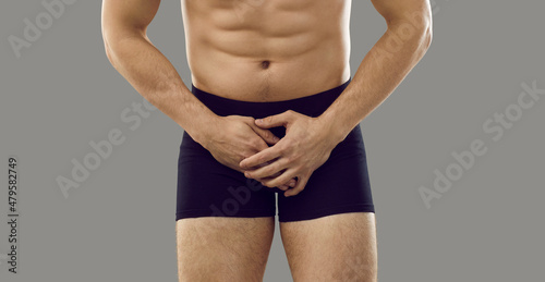 Canvas-taulu Man in underwear standing isolated on grey background covering his painful crotch area