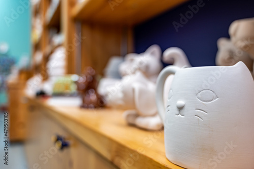 Row of blank unfinished ceramic figures on a studio shelf in a DIY store for painting.  photo