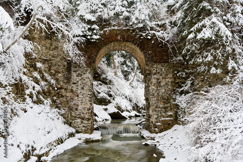 old stone bridge in winter forest in Ukrainian carphatians photo