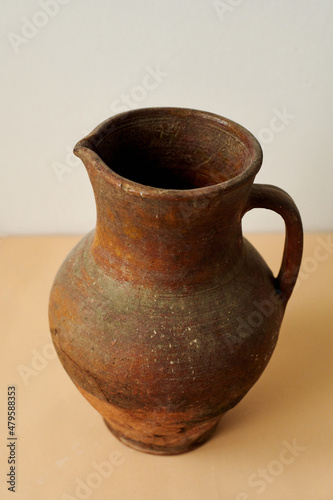 old ancient brown jug on white and  peachy background © Taras