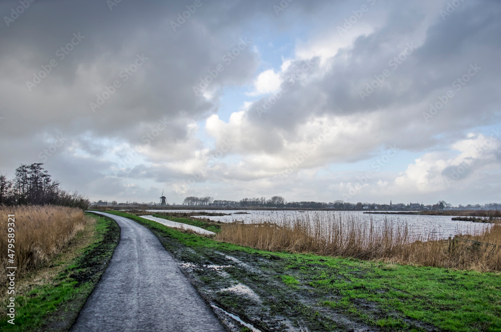 Narrow asphalt bicycle road under a dramatic sky in Krimpenerwaard polder in the Netherlands