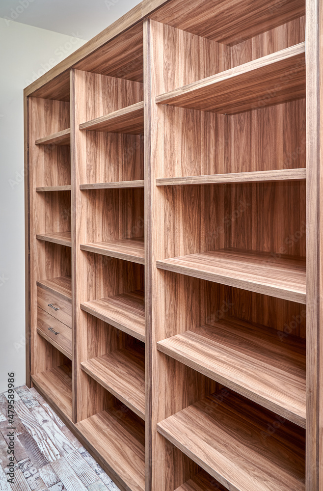 Elegant cabinet of walnut tree solid and veneer wood with empty shelves and drawers in walk-in closet in renovated apartment