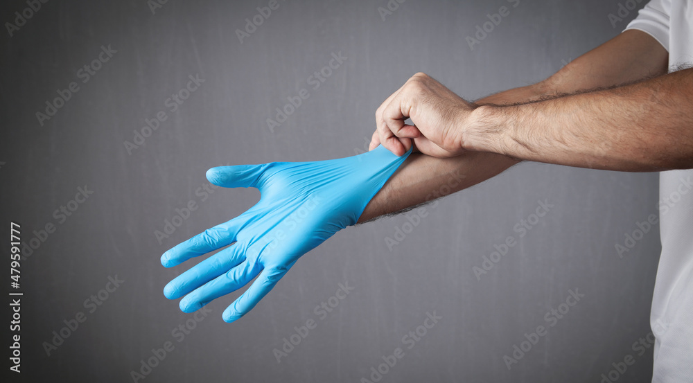 Hands of man putting on blue latex rubber gloves.