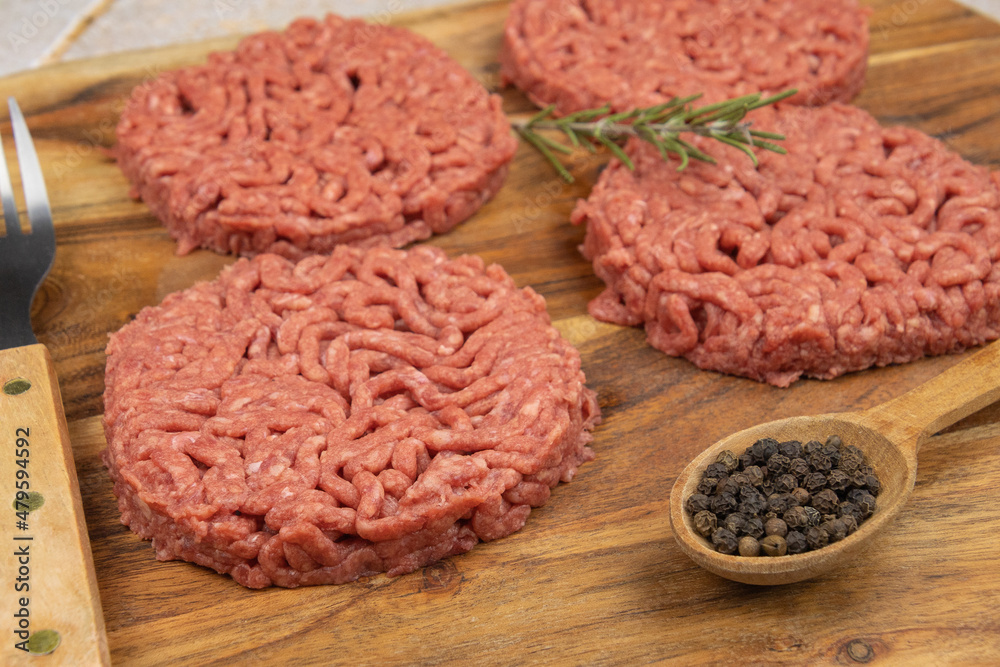 several raw hamburgers on a cutting board several raw hamburgers on a cutting board