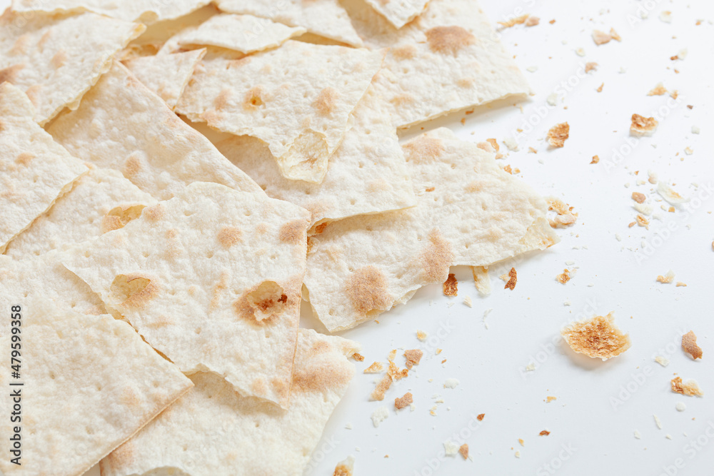 Dry flat bread broken in pieces and divided, with crumbs, on white background, Croatian traditional cuisine mlinci