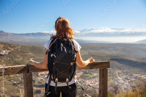 woman traveler with backpack looking at panoramic view on Sierra nevada in Spain