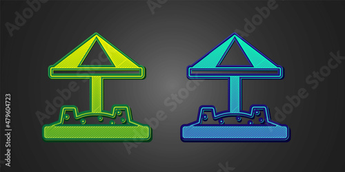 Green and blue Sandbox for kids with sand and umbrella icon isolated on black background. Vector