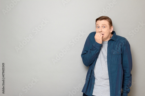 Portrait of shocked frightened blond mature man biting his nails