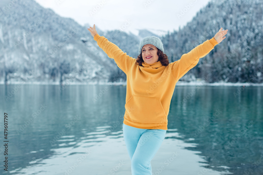 winter travel across Europe. portrait of a beautiful young woman on the shore of an alpine lake in winter. view of the alpine lake with snow. winter travel across Europe. portrait of a beautiful young woman on the shore of an alpine lake in winter. view of the alpine lake with snow.