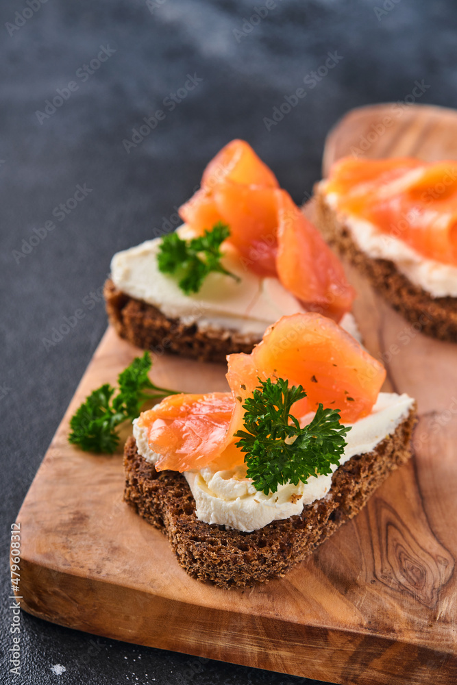 Mini sandwiches with salmon, curd cheese, parsley and rye bread in form of hearts. Valentine's day homemade creative food. Love breakfast design. Selective focus and copy space Mini sandwiches with salmon, curd cheese, parsley and rye bread in form of hearts. Valentine's day homemade creative food. Love breakfast design. Selective focus and copy space