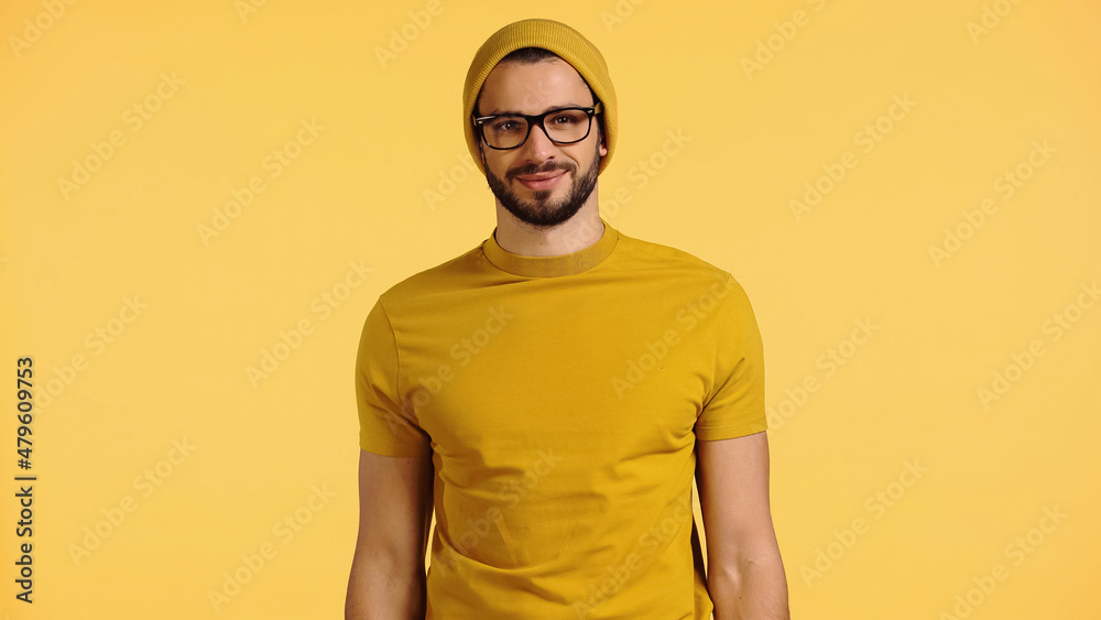happy young man in beanie hat, glasses and t-shirt isolated on yellow happy young man in beanie hat, glasses and t-shirt isolated on yellow