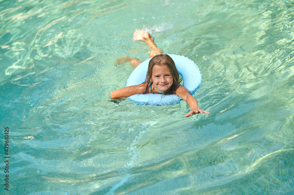 Sweet little girl swimming on a tube and smiling