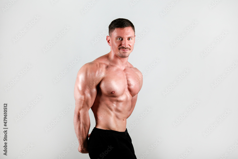 Professional bodybuilder posing over isolated white background. Studio shot of a fitness trainer flexing the muscles. Side Triceps pose. Close up, copy space.