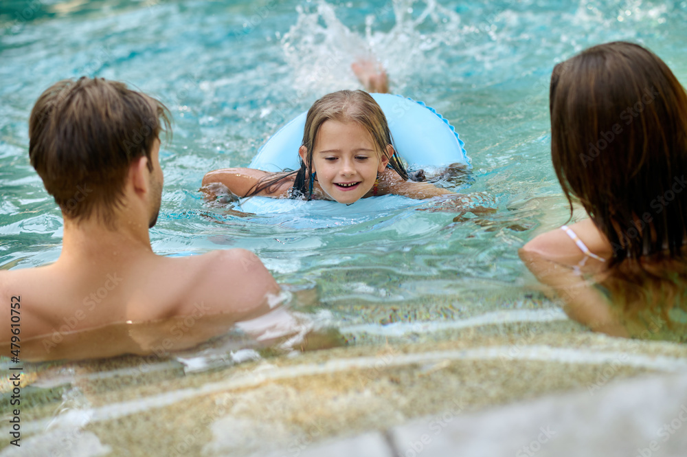 Parents teaching theri daughter to swim and looking involved Parents teaching theri daughter to swim and looking involved