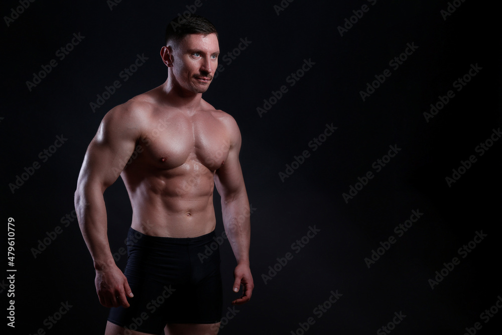 Professional bodybuilder posing over isolated black background. Studio shot of a fitness trainer flexing the muscles. Close up, copy space. Professional bodybuilder posing over isolated black background. Studio shot of a fitness trainer flexing the muscles. Close up, copy space.