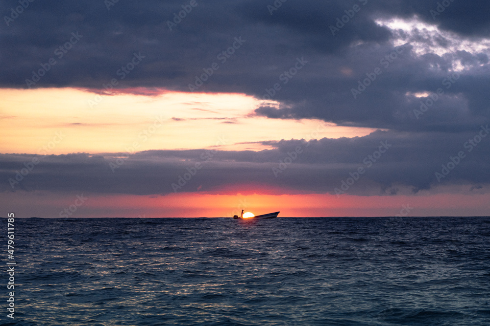 Pescador en su barco al amanecer en el mar