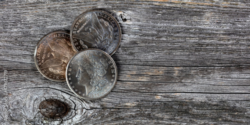 Εκτύπωση καμβά Collection of US Morgan silver dollars with patina finish on weathered wooden bo