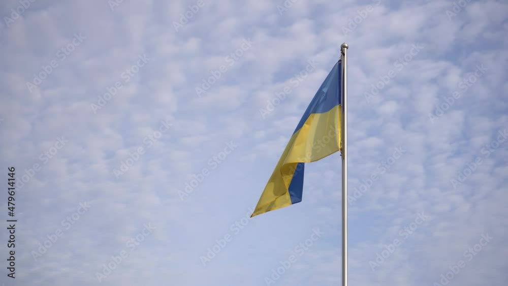 Under a hazy blue sky, Ukrainian flag is waved in the breeze. Under a hazy blue sky, Ukrainian flag is waved in the breeze.