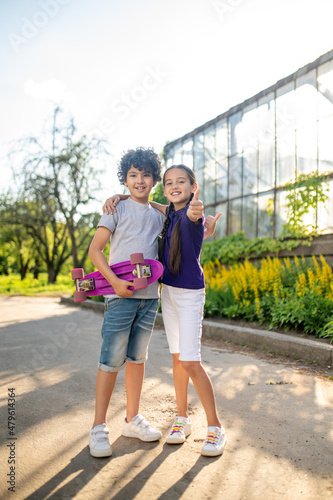 Young skateboarder and his friend making a thumbs-up sign
