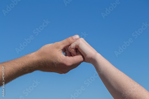 Couple hands held together on blue sky background