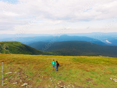 Aerial view of the Great Green Ridge. Guy and Girl Standing on a Big Hill against the Backdrop of a Huge Mountain Landscape