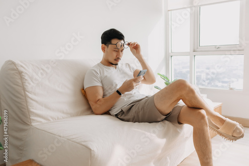 Middle age Asian man with long eye sight try to look at the smartphone.