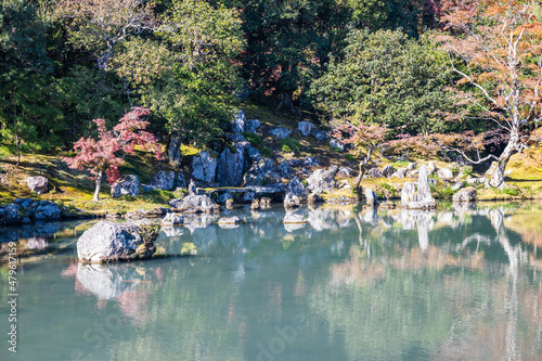 An autumn garden at the Tenryu-Ji Temple in Kyoto Japan with the colors of fall reflecting in the calm water of the pond. photo