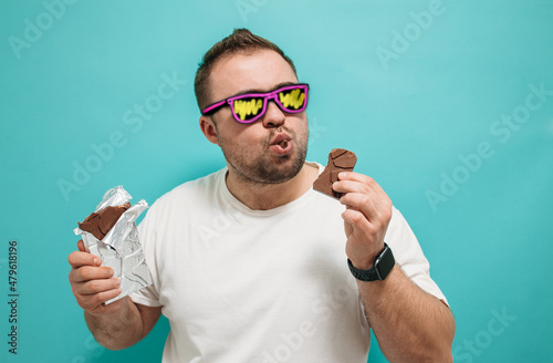Konstfotografi Overweight funny man biting large of chocolate with pleased joyful look