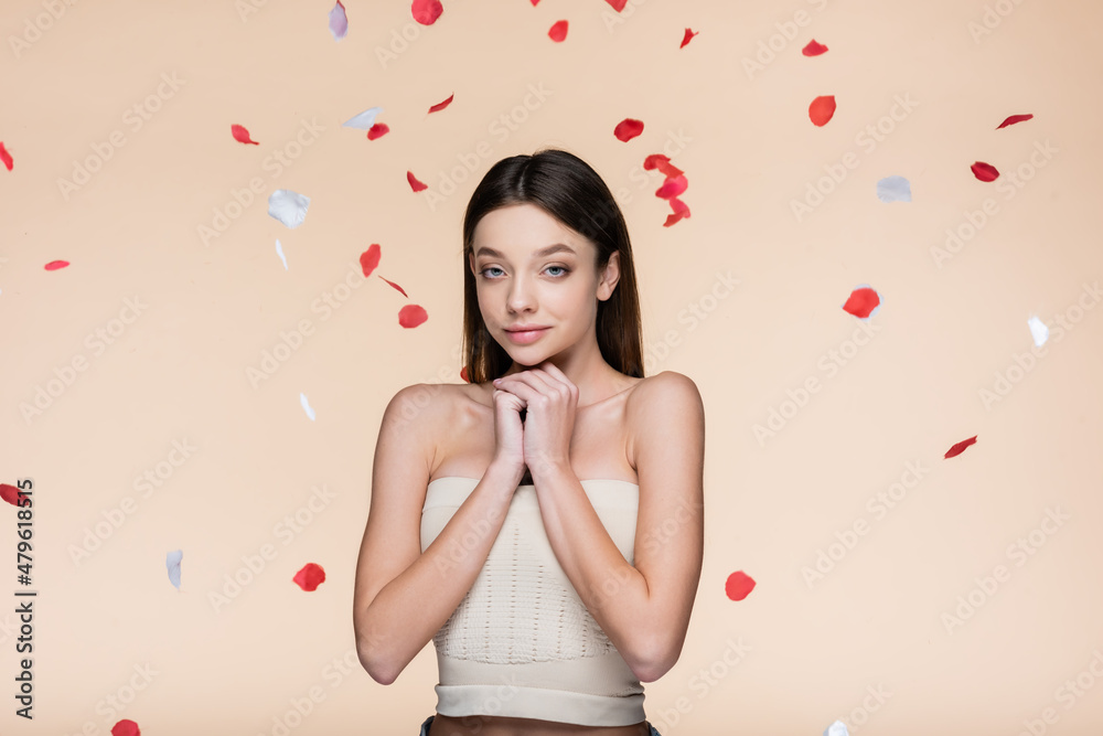 sensual young woman in crop top near falling rose petals on beige sensual young woman in crop top near falling rose petals on beige