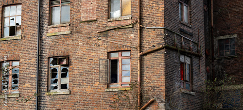 historic old factory mill building broken down and decaying with broken glass and windows