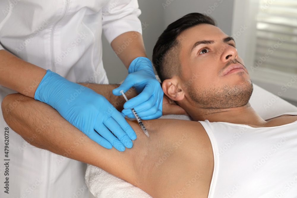 Cosmetologist injecting man's armpit in clinic. Treatment of hyperhidrosis Cosmetologist injecting man's armpit in clinic. Treatment of hyperhidrosis