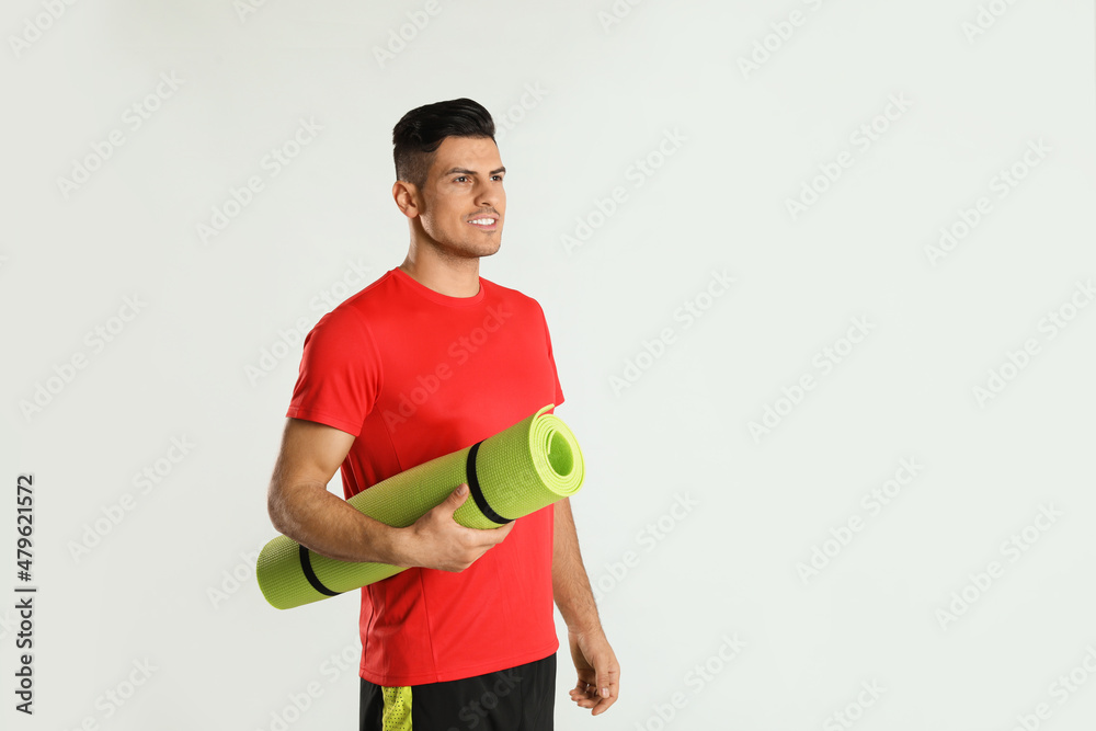 Handsome man with yoga mat on light background. Space for text