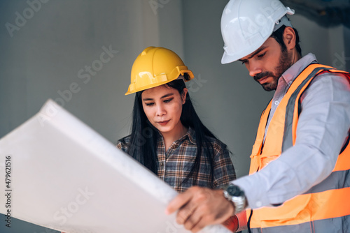 Civil engineer and construction worker manager holding digital tablet and blueprints , talking and planing about construction site. Cooperation teamwork concept.