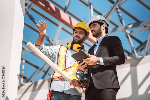 Civil engineer and construction worker manager holding digital tablet and blueprints , talking and planing about construction site.  Cooperation teamwork concept.