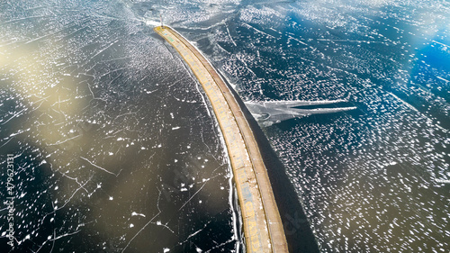 Aerial view of a pier with a lighthouse on a frozen lake