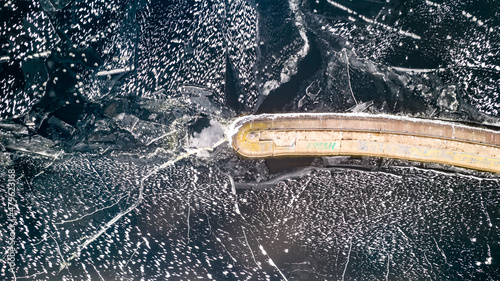Aerial view of a pier with a lighthouse on a frozen lake