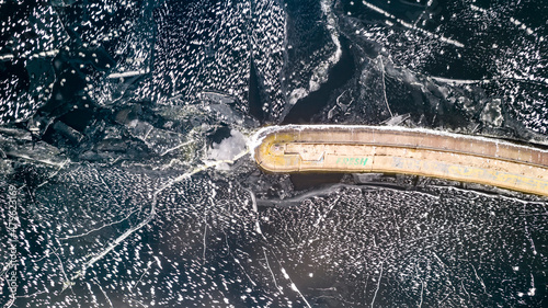 Aerial view of a pier with a lighthouse on a frozen lake