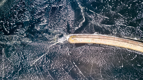 Aerial view of a pier with a lighthouse on a frozen lake