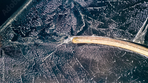 Aerial view of a pier with a lighthouse on a frozen lake