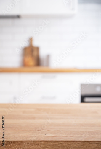 Wooden oak countertop with free space for mounting a product or layout against the background of a  blurred white kitchen
