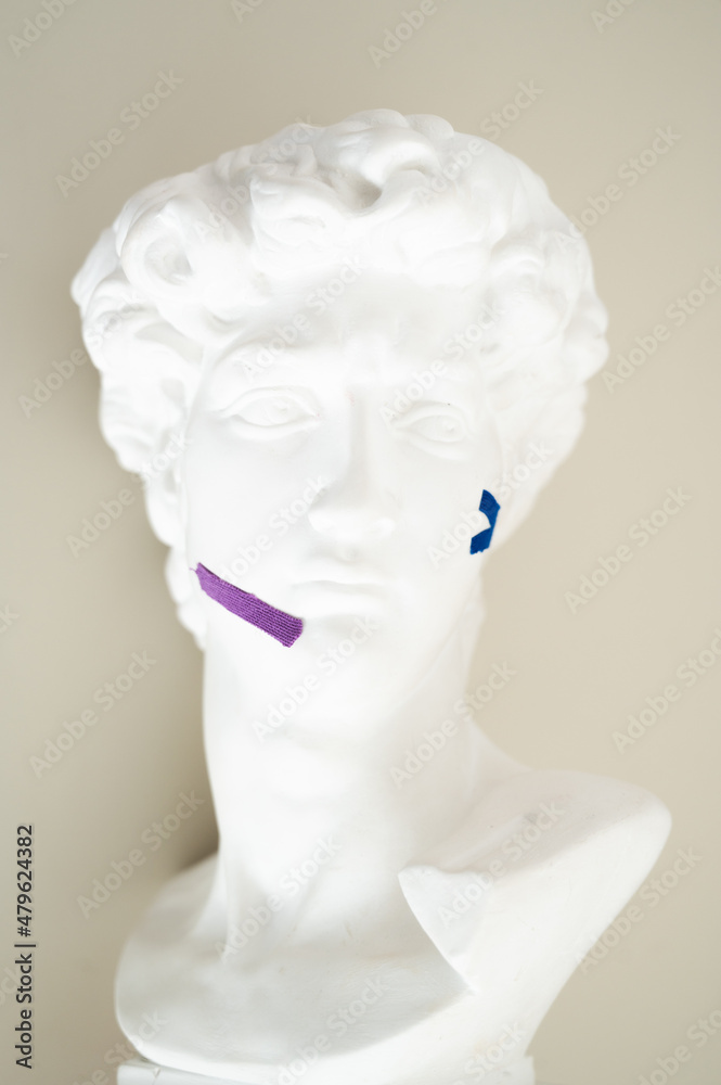 Gypsum statue of head with kinesio tape. Face-taping, lifting treatment on face concept
